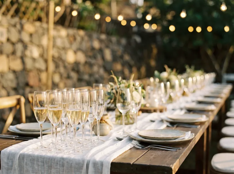 occasion-tenerife-celebrate-04 Long festively set table with a row of filled champagne glasses, string lights and stone wall in the background, Tenerife