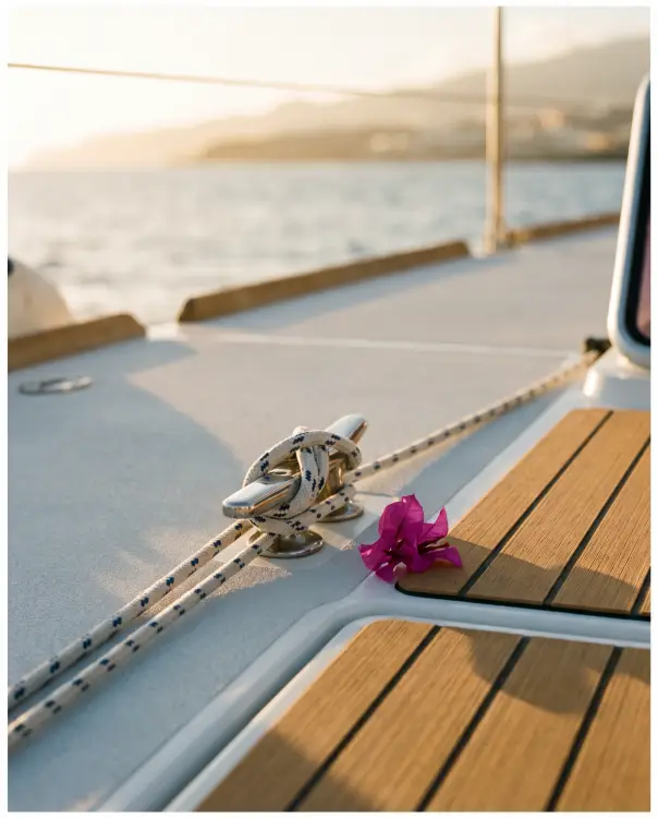 elopement-micro-weddings-02 Close-up of a modern sailing yacht deck in Tenerife with white rope coiled around a stainless steel cleat and a bougainvillea blossom