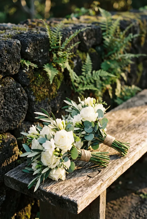 Two matching small bouquets of white flowers and green foliage lying side by side on a wooden bench in a finca garden in Tenerife